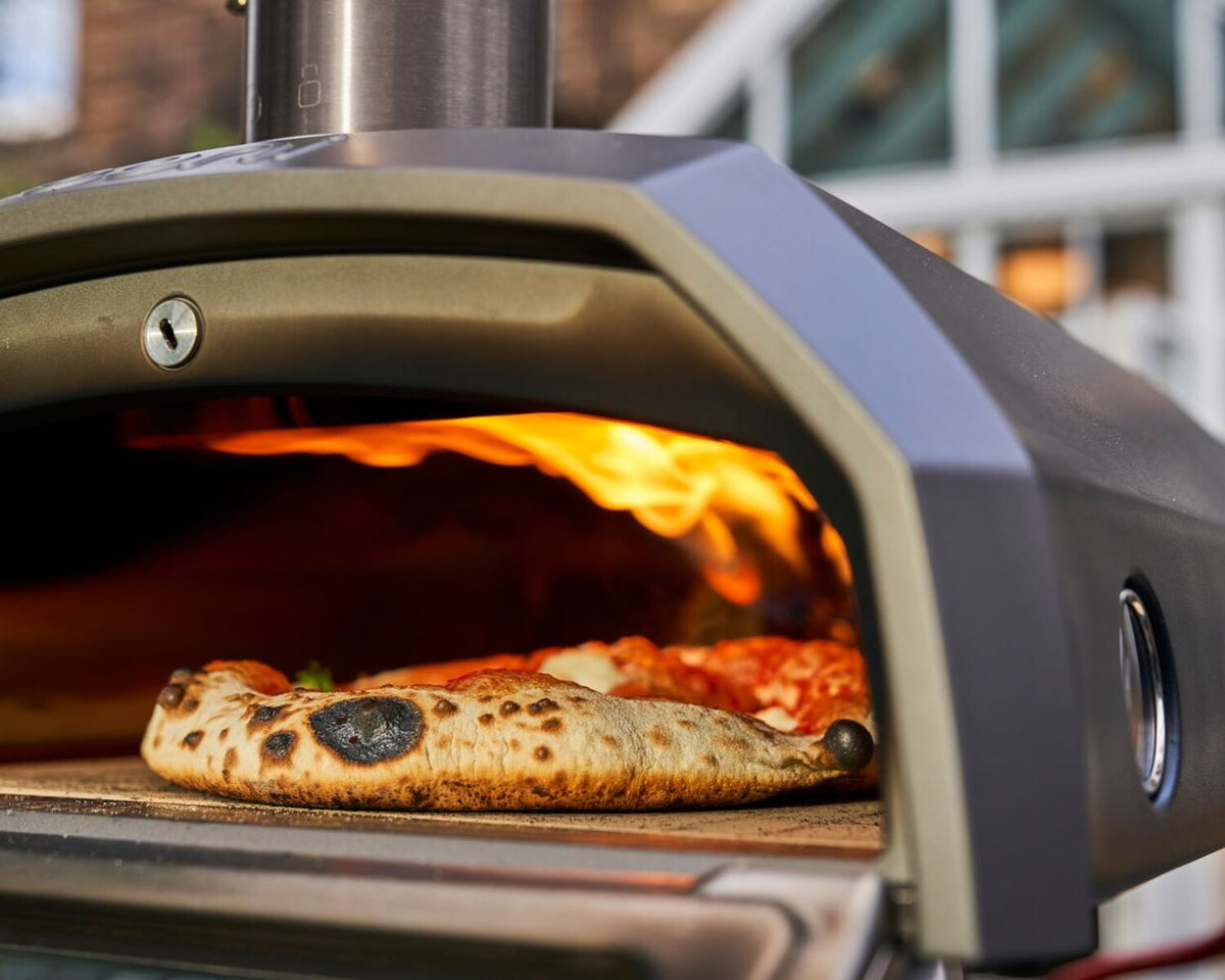 Karu 12g ooni ovens cooking a homemade pizza outside a house