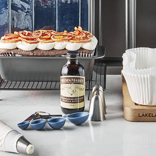 A bottle of vanilla extract surrounded by Lakeland bakeware and utensils
