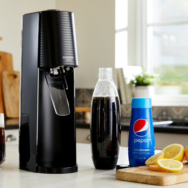 A Sodastream Terra with canister and bottle of syrup flavouring on a kitchen counter.