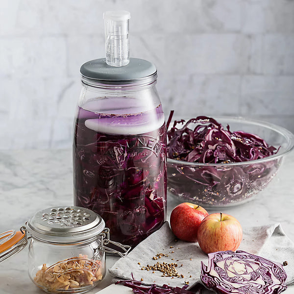 A kilner fermentation jar is being used to make picked red onions. The jar is surrounded by ingredients to make it.