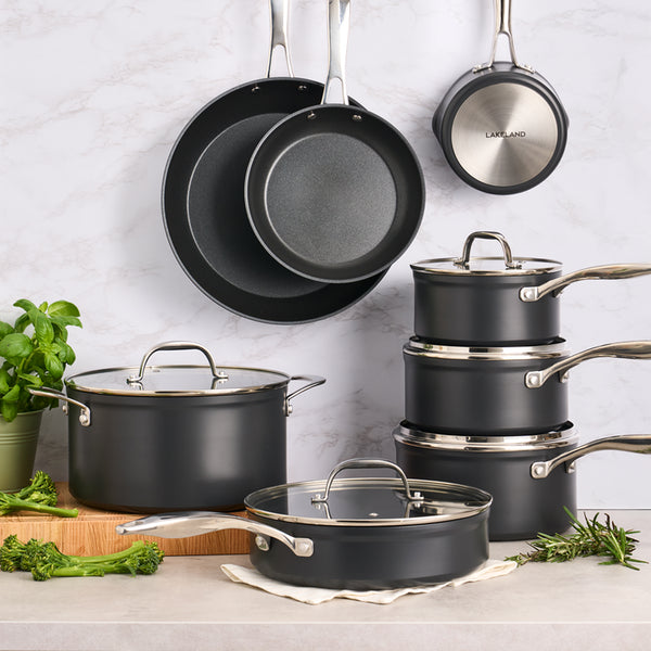 A range of black pans with silver handles displayed together.